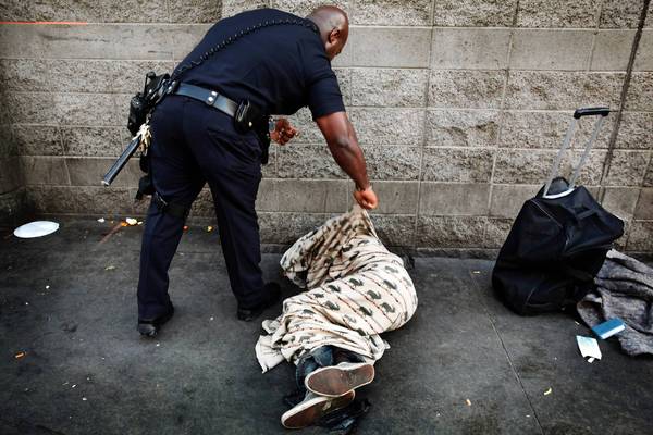 LAPD Officer Deon Joseph tries to wake a man on skid row.